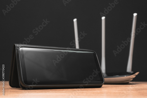 Blank screen mobile phone and wifi router on the table close up.