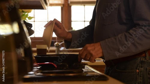 Older man Cooking Egg Breakfast with cast iron skillet on a cool bright morning.
