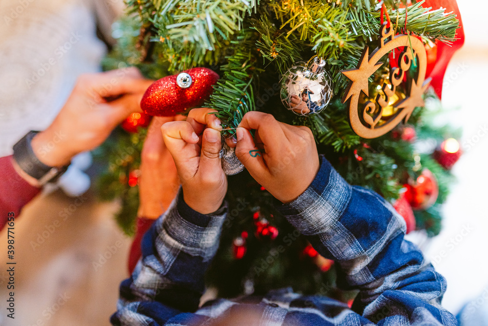 cute little children hands decorating christmas tree at home during holidays season. childhood christmas time at home. in winter with warm natural soft light