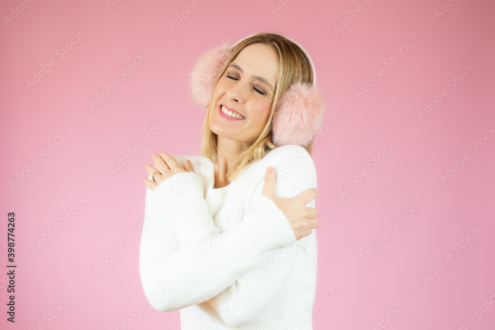 young pretty blonde woman feeling in love, smiling, cuddling and hugging self, staying single, being selfish and egocentric against pink flat wall young pretty blonde woman feeling in love, smiling, cuddling and hugging self, staying single, being selfish and egocentric against pink flat wall