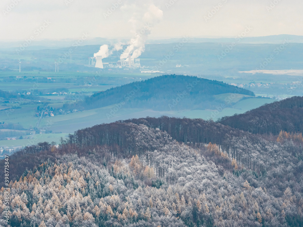 Dark blue hills with hoarfrost cover and coal power plant Turow in Poland smoking