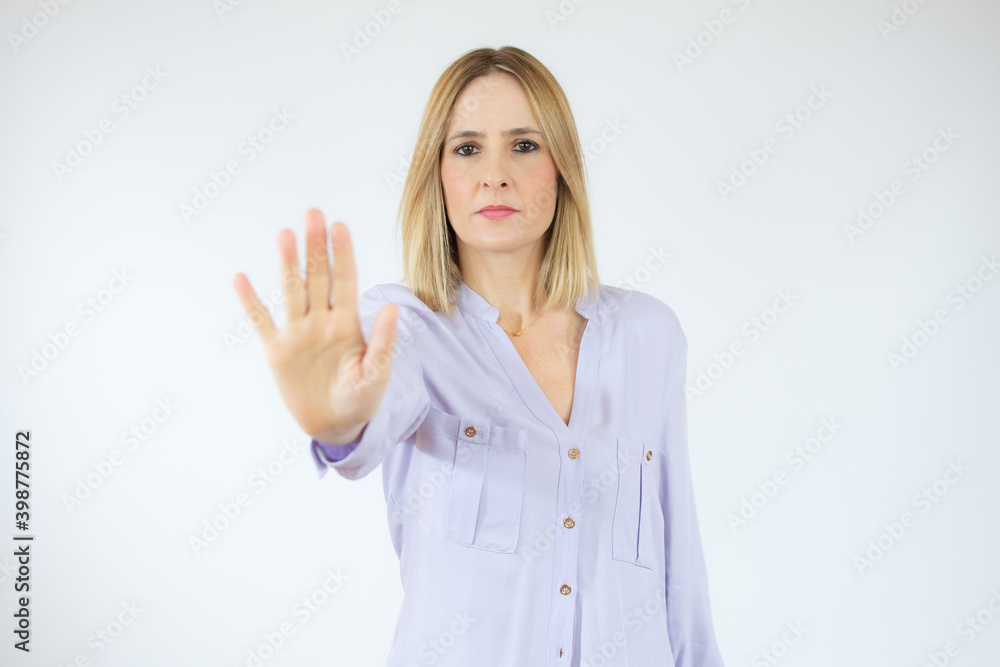 Portrait of a serious young caucasian woman standing with outstretched hand showing stop gesture isolated over white background Portrait of a serious young caucasian woman standing with outstretched hand showing stop gesture isolated over white background