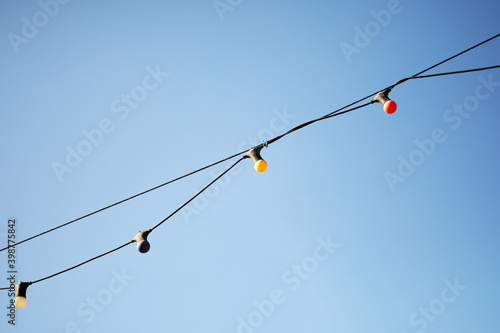 Colored light bulbs garlands on blue sky background