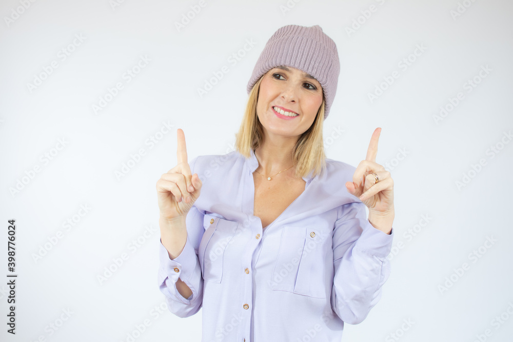 Portrait of a happy young woman wearing winter hat pointing fingers up at copy space isolated over white background Portrait of a happy young woman wearing winter hat pointing fingers up at copy space isolated over white background