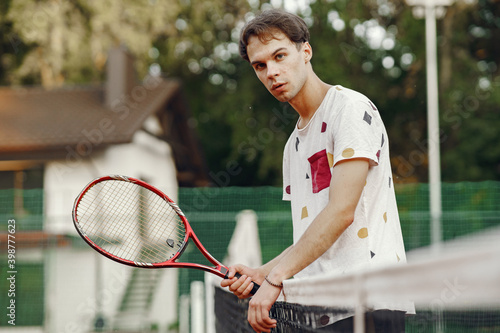 Great day to play Cheerful young man in t-shirt. Guy holding tennis racket and ball. © hetmanstock2
