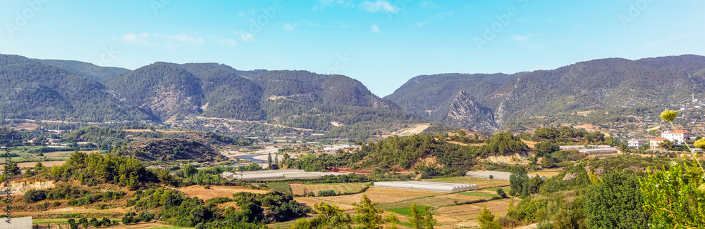 A panorama view across the Alaharan valley looking towards the hilltop Alara fort in the distance in Turkey in summertime
