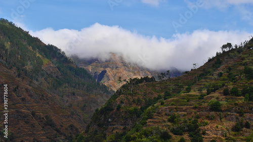 Beautiful view of gorge "Ribeira da Ponta do Sol", a popular tourist destination for hiking, on southern coast of Madeira island, Portugal with steep slopes and trees on the cloud covered mountains.