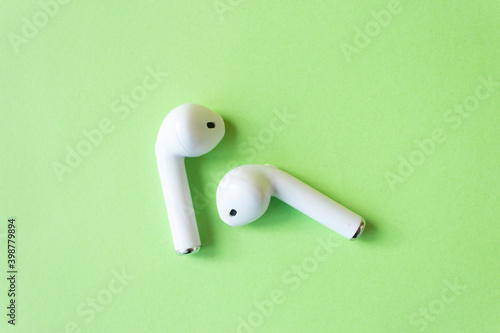 Wireless white headphones on a green background. 