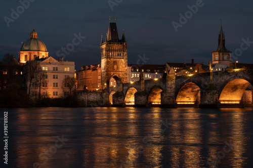 .Charles Bridge in the early evening and illuminated street lights in the center of Prague and reflections on the river Vltava light