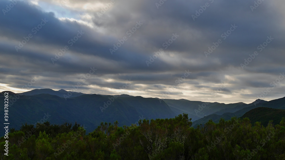 Beautiful panoramic view of the western mountain range of Madeira island, Portugal with mountains covered by dense green vegetation on cloudy day.