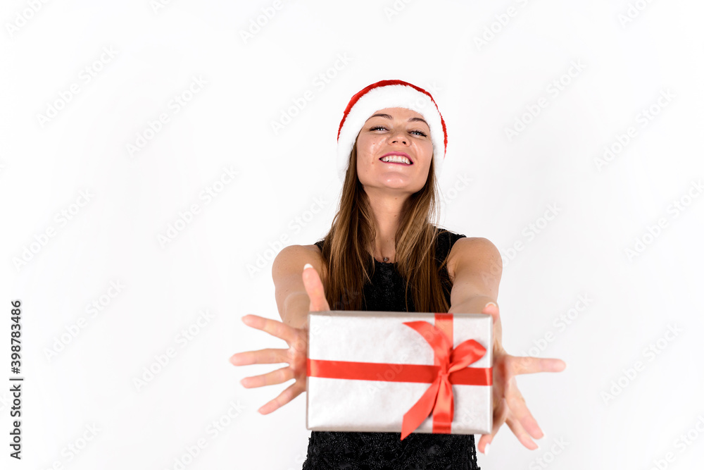Portrait of a young woman showing gift box and wearing red santa hat. Isolated on white background Portrait of a young woman showing gift box and wearing red santa hat. Isolated on white background