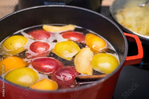 Foto Preparing delicious hot apple cider with cinnamon in a red pan