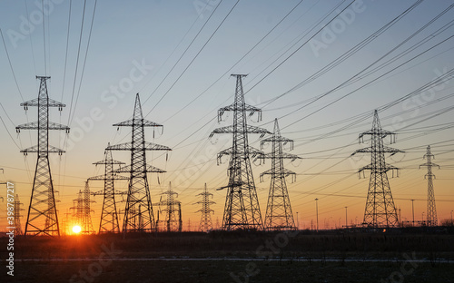 Silhouettes of a high-voltage electric tower against the background of the rising sun and sky. Selective focus.