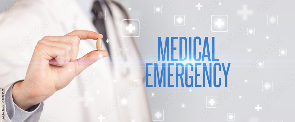 Close-up of a doctor giving a pill with MEDICAL EMERGENCY inscription, medical concept Close-up of a doctor giving a pill with MEDICAL EMERGENCY inscription, medical concept