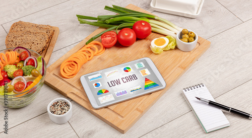 Organic food and tablet pc showing LOW CARB inscription, healthy nutrition composition