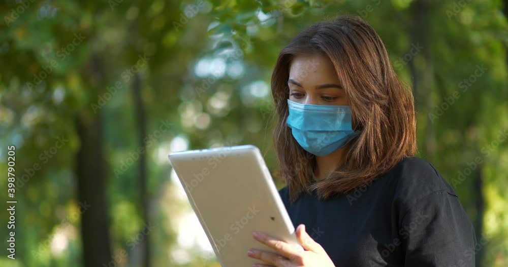 Young woman in blue medical protective mask work on tablet computer. Cinema 4K 60fps video Young woman in blue medical protective mask work on tablet computer. Cinema 4K 60fps video