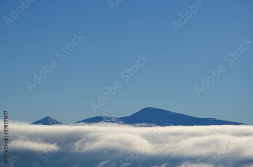 Mountain range covered with clouds in sunny day. Carpathians.