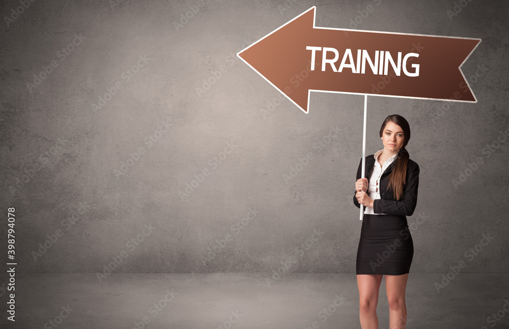 Young business person in casual holding road sign with TRAINING inscription, business direction concept Young business person in casual holding road sign with TRAINING inscription, business direction concept