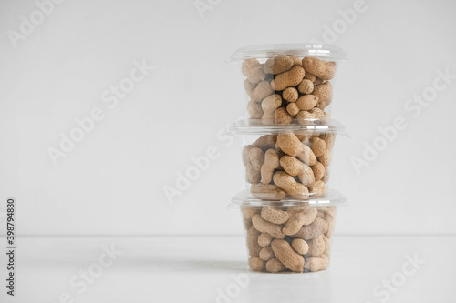 Dry peanuts in a transparent plastic bowls on a white background. Copy, empty space for text