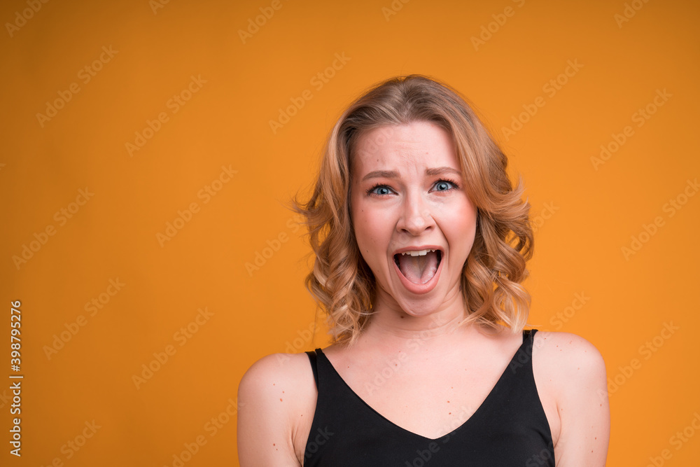Portrait of a blonde girl with an open mouth laughing on an orange background Portrait of a blonde girl with an open mouth laughing on an orange background