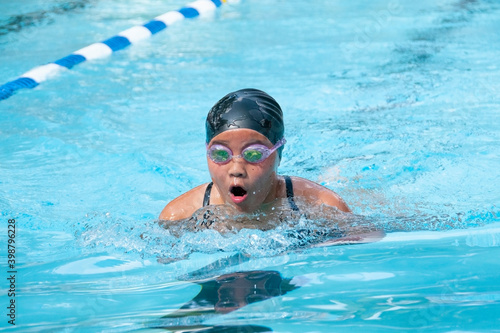 Teenage girl swimming breast stroke at a swim meet