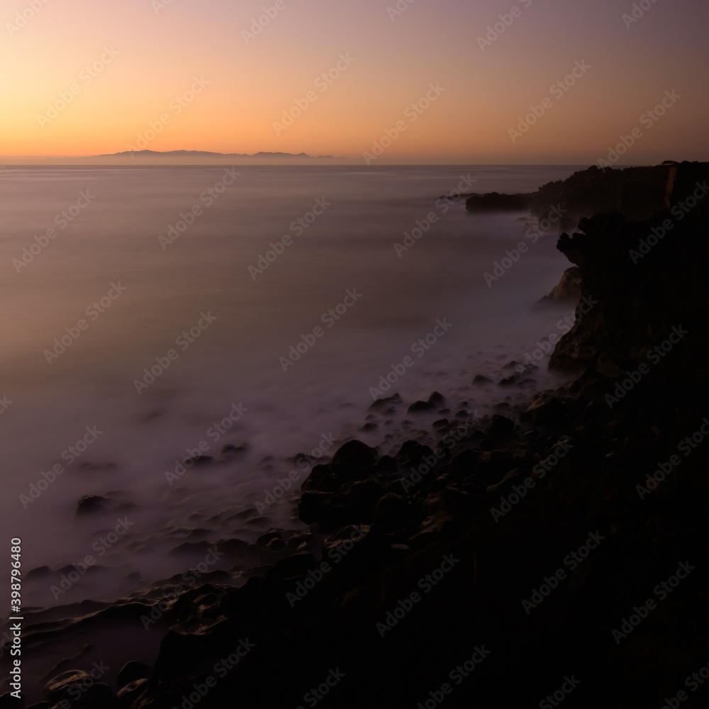 Coastal landscape long exposure photography of the sunrise in a rocky cliff in Candelaria, Tenerife, Canary Islands, Atlantic Ocean. Silk effect on water. Coastal landscape long exposure photography of the sunrise in a rocky cliff in Candelaria, Tenerife, Canary Islands, Atlantic Ocean. Silk effect on water.