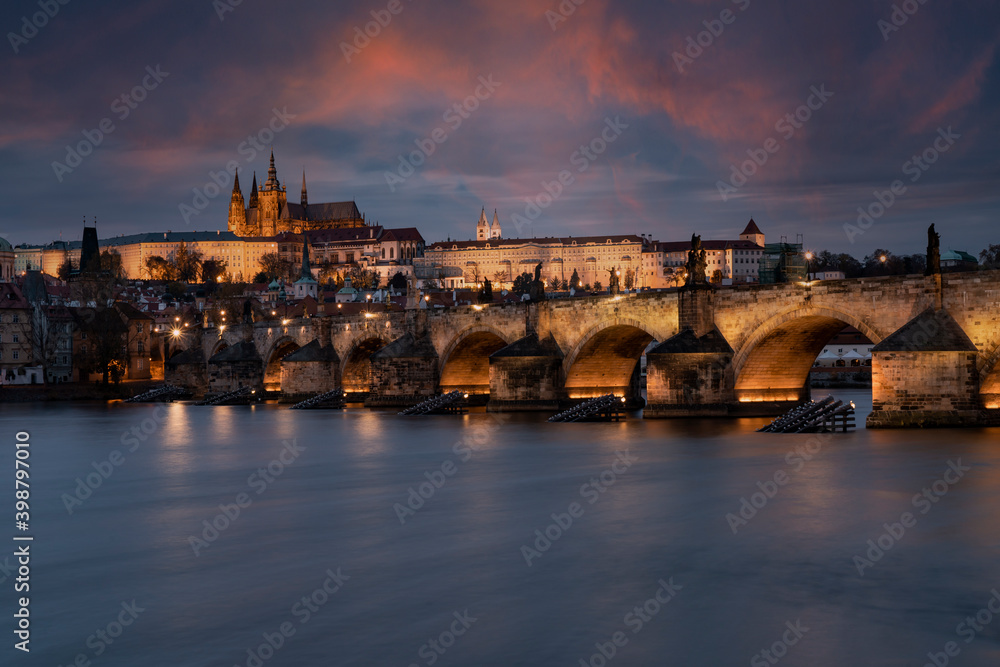 prague castle and charles bridge and st. vita church lights from street lights are reflected on the surface of the vltava river in the center of prague at night in the czech republic