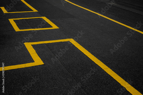 Abstract texture composition in the form of yellow boundary warning lines painted with paint on a dark gray background. The natural texture of the bituminous coating on the roof of the house.