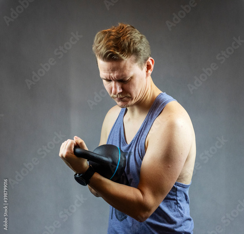 Caucasian man looking at a a black kettlebell while exercising