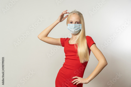 Teenage girl with blond hair in the crown and a mask from coronavirus