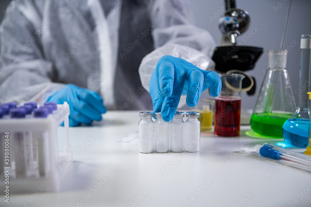 Development and search for drug for coronavirus. Chemist examining ampoule of powdered antibiotic for injection. Treating bacterial infection with medications. Covid 19 health and treatment concept Development and search for drug for coronavirus. Chemist examining ampoule of powdered antibiotic for injection. Treating bacterial infection with medications. Covid 19 health and treatment concept
