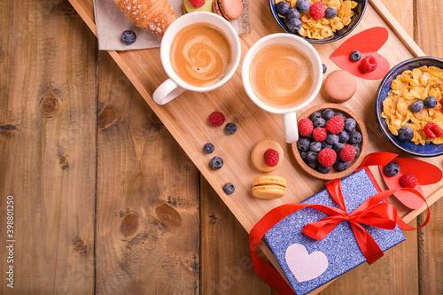 Breakfast for lovers. Delicious Valentine's Day surprise for your loved one. Coffee, muesli with berries and sweets on a wooden table. Copy space. Top view. High quality photo
