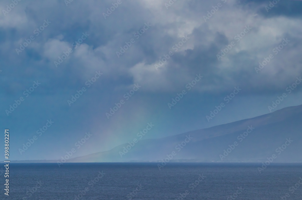 Colorful faint rainbow acdross the ocean and Molokai seen from Maui. Colorful faint rainbow acdross the ocean and Molokai seen from Maui.