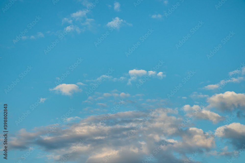Fototapeta premium light blue sky, with small tufts of white clouds floating and shaded clouds on the horizon.