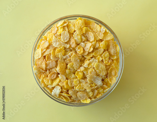 Bowl of cereal corn flakes on a yellow background. Flat lay style