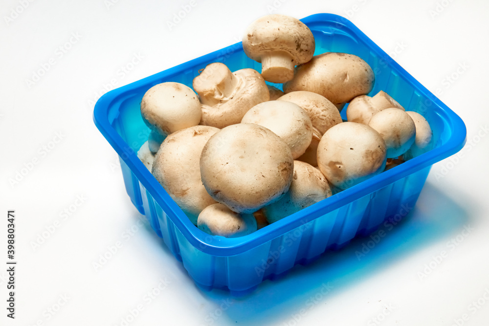 Porcini champignons in a plastic container on a light background. Porcini champignons in a plastic container on a light background.