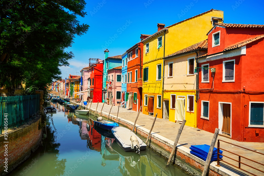 Burano traditional vivid colorful houses vibrant colors island tourism landmark cityscape. Sea canal with boats and bright paint facade old historic scenic place. Venice Italy