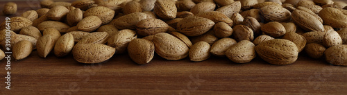 Almonds in a shell. Close up..A heap of almond nuts as a background..Unshelled almonds on wooden background..Large banner format.