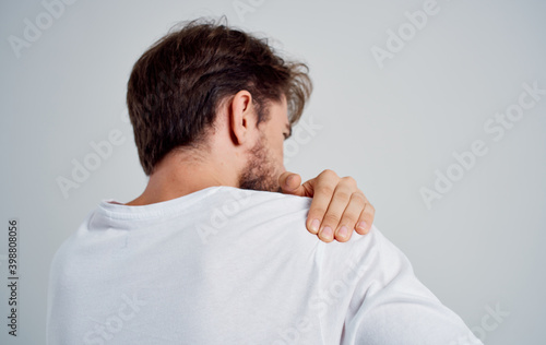 man shoulder pain t-shirt back view light background