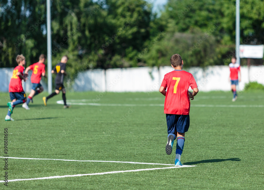 Boy in red uniform playing football. soccer player kicking the ball