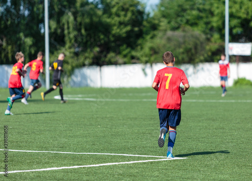 Boy in red uniform playing football. soccer player kicking the ball © Natali
