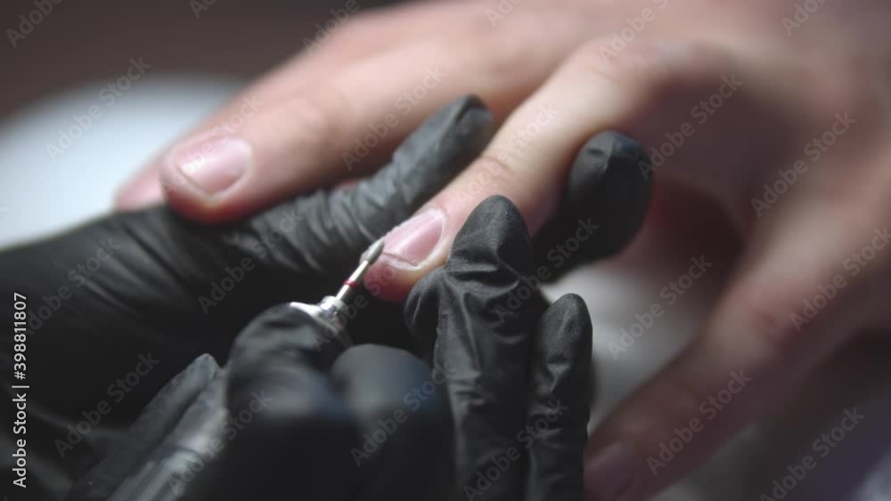 Manicurist doing manicure on male hands using a small drilling device Manicurist doing manicure on male hands using a small drilling device