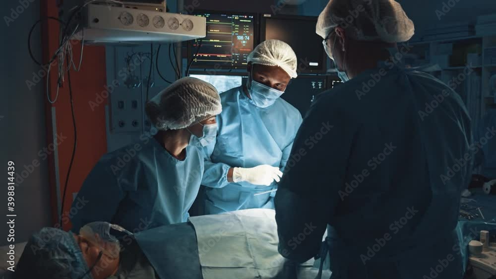 Professional surgeons and assistants talking and using digital tablet computer during surgery at operation theatre. They working in modern hospital operating room. Modern technologies at the medicine Professional surgeons and assistants talking and using digital tablet computer during surgery at operation theatre. They working in modern hospital operating room. Modern technologies at the medicine