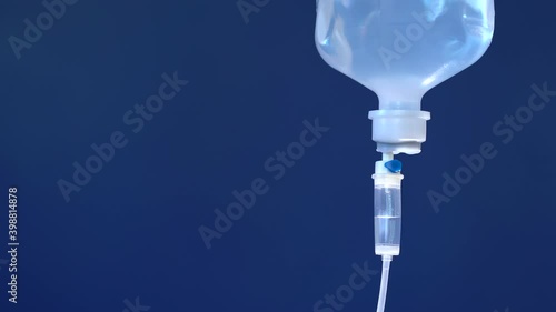Closeup of IV drip in hospital, Intravenous saline solution, IV loading dose blue background.
