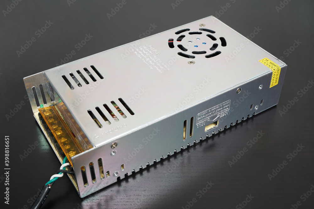 Inexpensive 14 Volt DC switching power supply on black desk Inexpensive 14 Volt DC switching power supply on black desk