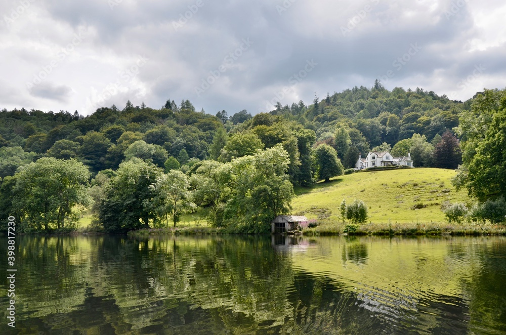 Beautiful house on a green hill among tees with a lake view.