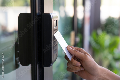 young woman using RFID tag key, fingerprint and access control  to open the door in a office building photo