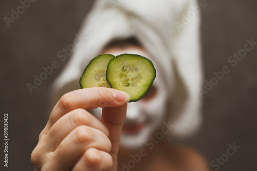 A woman applies a face mask and uses cucumber slices to solve skin problems around the eyes. An ecological, vegan, vegetarian way of life. Self-care and lifestyle, solving skin issues.