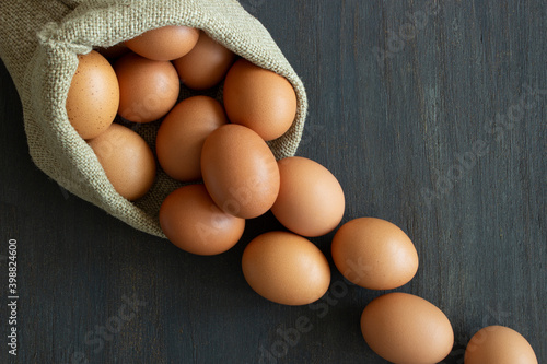 Brown eggs rolling from a sack on dark background photo