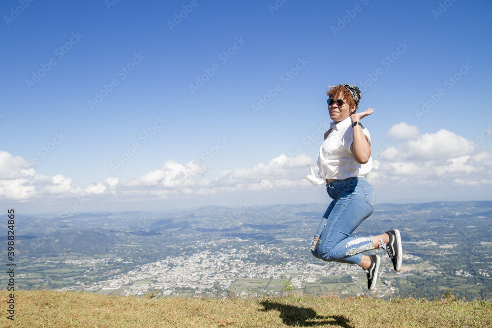 one attractive latin american young women outdoors with sunglasses happy and jumping in a summer day vacation trip with view of distant dominican city with nature background one attractive latin american young women outdoors with sunglasses happy and jumping in a summer day vacation trip with view of distant dominican city with nature background